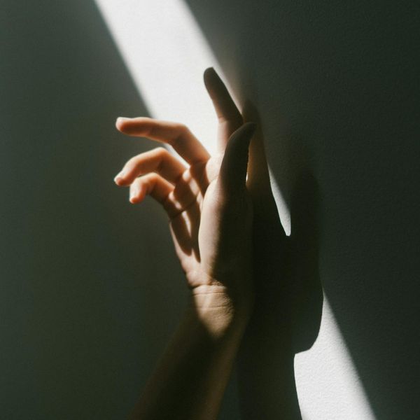 Abstract silhouette of a person stretching in a dark room.